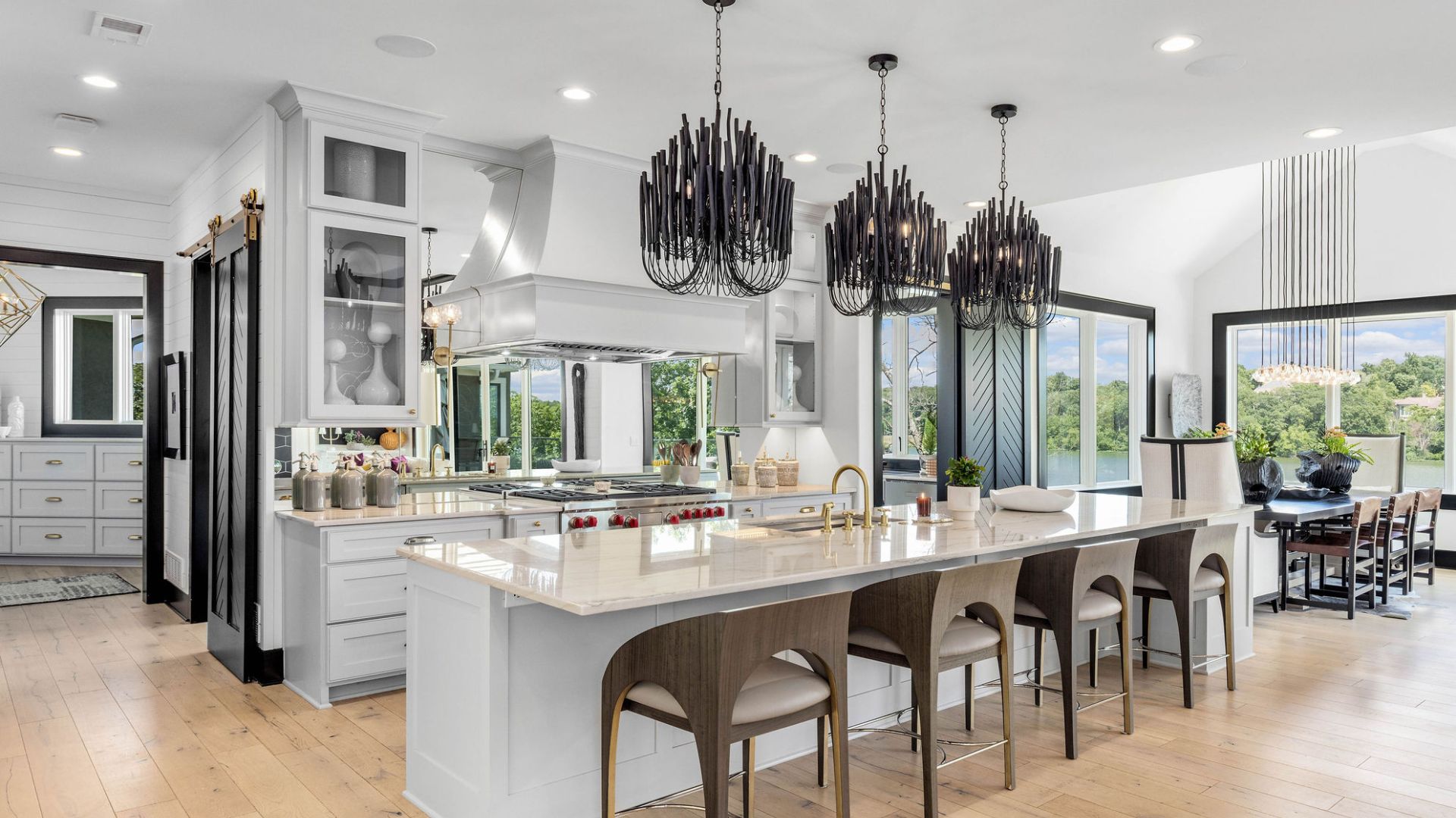 Photo of modern kitchen with striking lights and mirrored accents. Lots of natural light.
