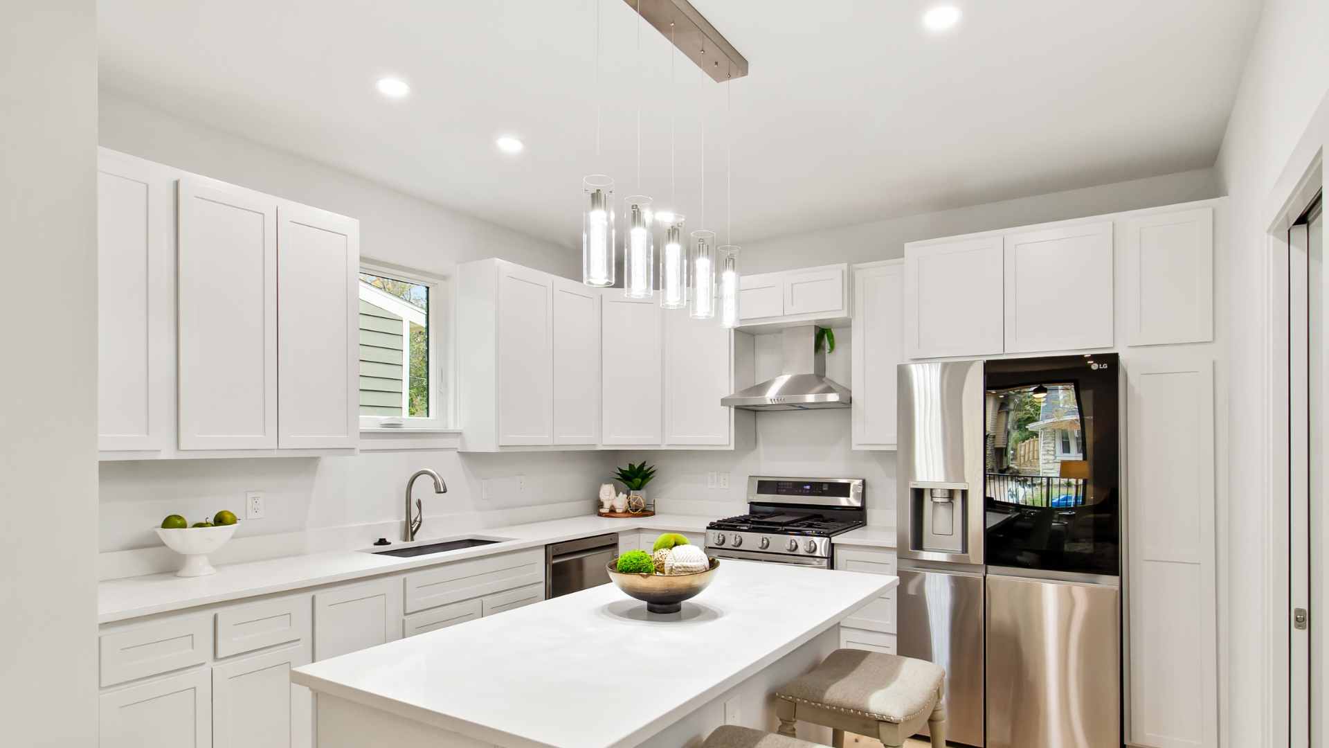Photo of a modern kitchen in a newly built home with white cabinets and modern light fixtures.