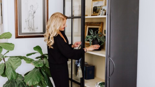 Woman placing a plant inside an armoire while staging a home.