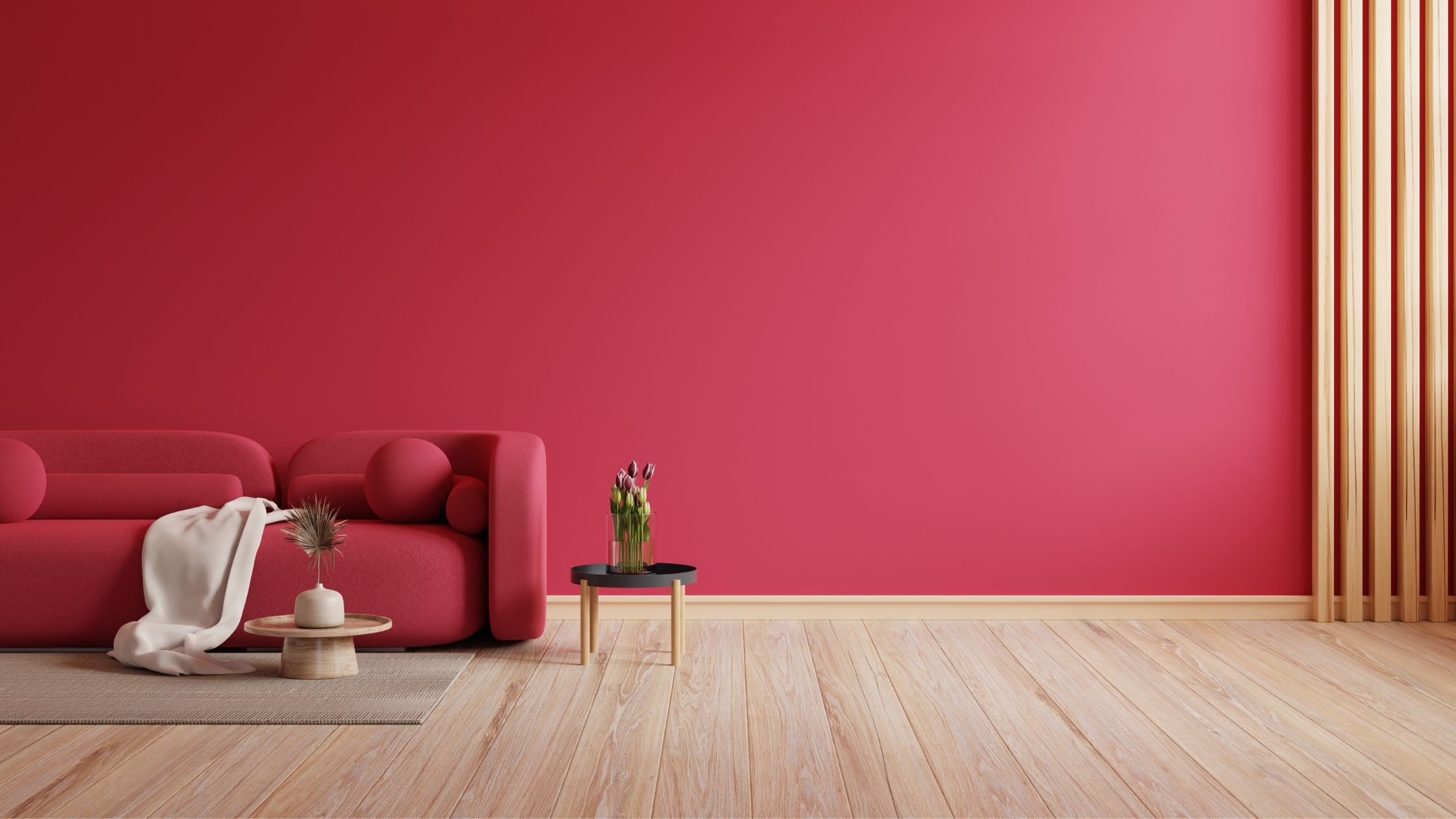 Simple living room with bright pink wall paint, matching pink couch and light hardwood floors.